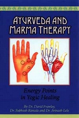 Paperback book "Ayurveda and Marma Therapy" by Lotus Press on a wooden table with a soft focus background.